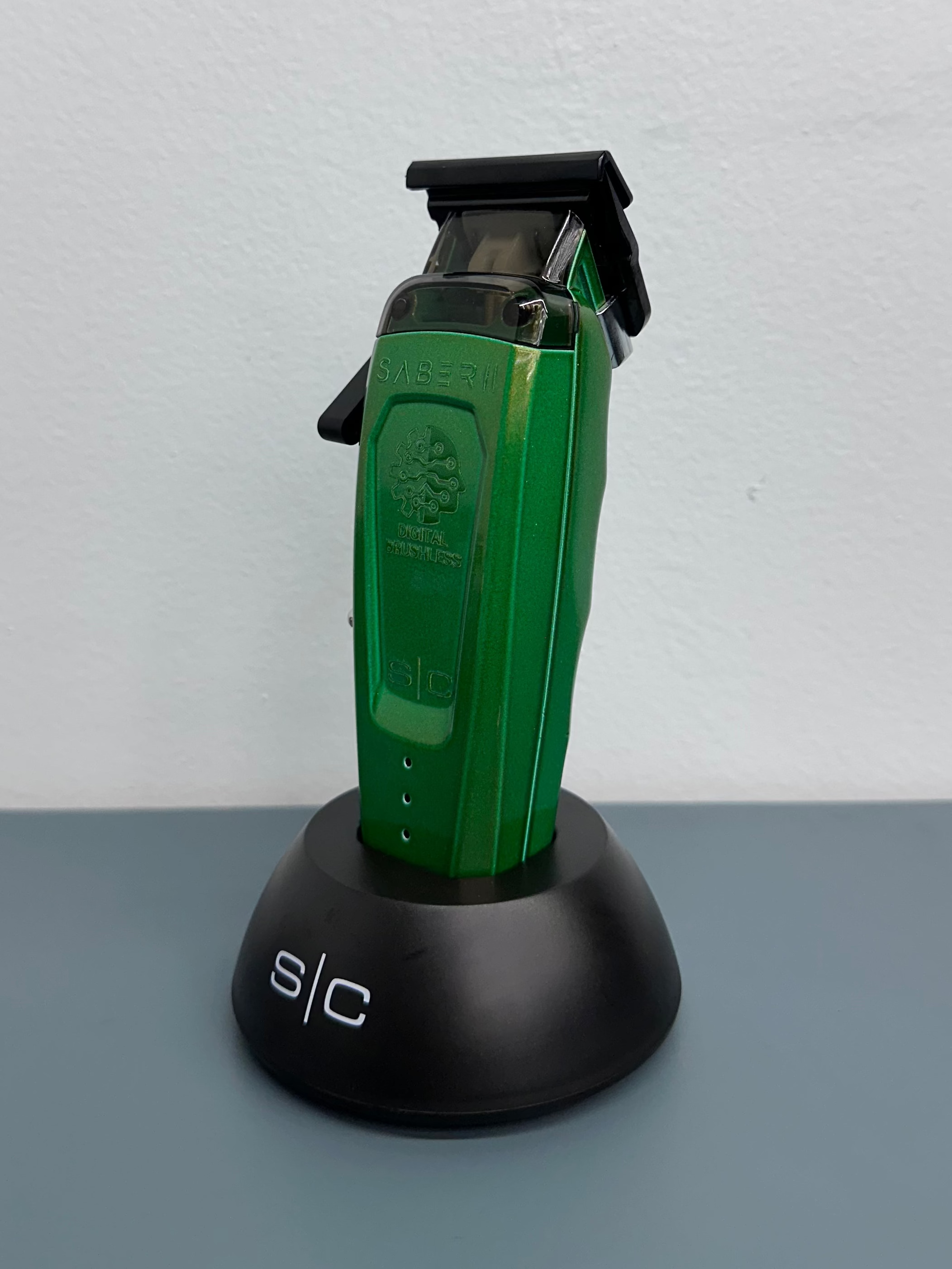 Green hair trimmer on a black stand against a white background